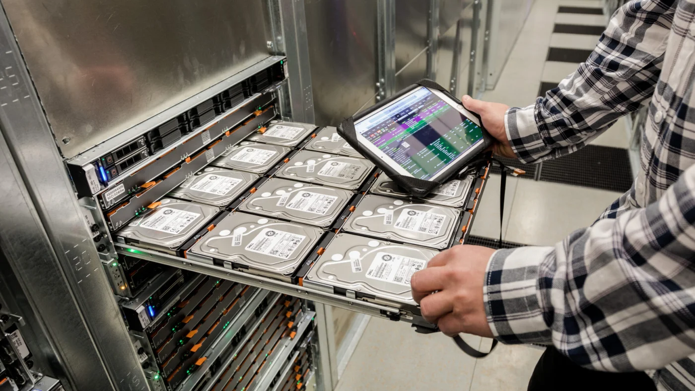 A technician checks server hard drives using a tablet